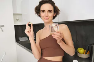 mulher com copo de água e cápsula 