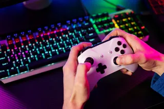 persona sosteniendo un controlador frente a teclado