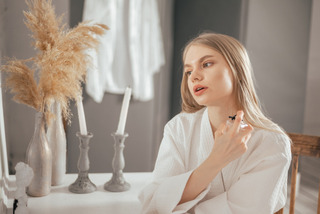 Mulher passa perfume em uma penteadeira