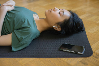 Mulher usando airpods enquanto faz yoga