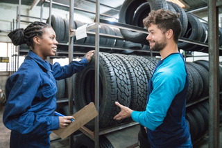 Homem e mulher conferem qualidade de pneus em fábrica