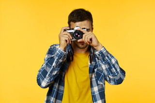 Hombre tomando una fotografía sobre fondo amarillo