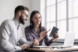 Dos personas usan una tablet y una notebook para su trabajo