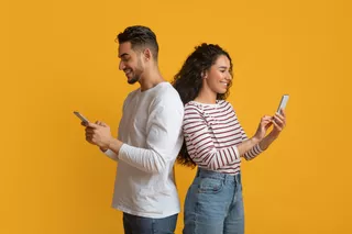 Una mujer y un hombre sonrientes usan sus celulares
