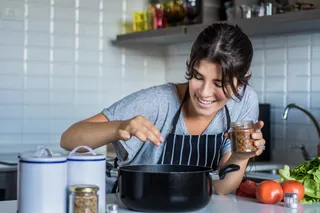 Mujer cocinando con una olla en la cocina.