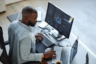 Homem utiliza notebook e PC para realizar trabalho