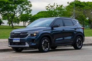 Camioneta SUV negra en la calle con árboles de fondo.