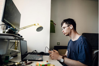 Joven jugando videojuegos con notebook y computador