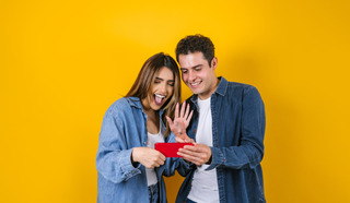 Hombre y mujer felices utilizando un celular rojo