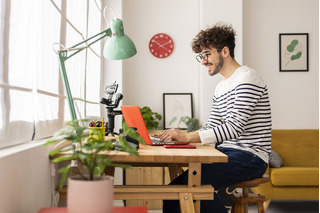 Joven trabajando en un escritorio junto a un computador