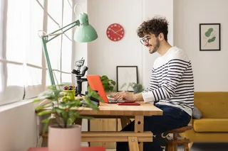 Joven trabajando en un escritorio junto a un computador