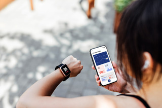 Mulher checa os dados da atividade física no smartwatch e no celular.