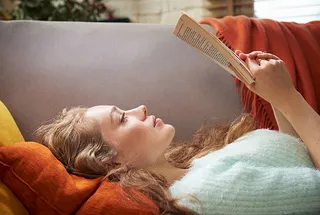 Joven leyendo un libro sobre el sofa