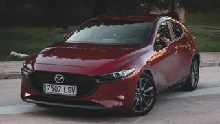 Mazda 3 sedán color rojo en carretera, seminuevo confiable para comprar en México.