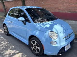 Fiat 500e eléctrico en color azul cielo estacionado en una calle urbana.