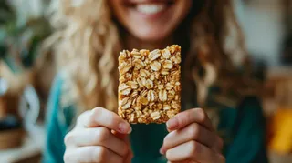 pessoa sorrindo segurando uma barra proteíca caseira