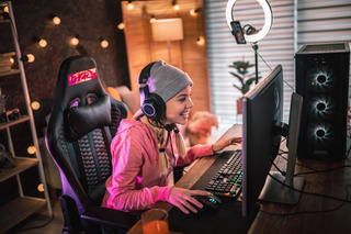 Mulher usa cadeira gamer para jogar em frente ao computador.