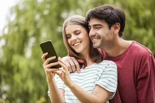 Una pareja sonriente utiliza un celular al aire libre