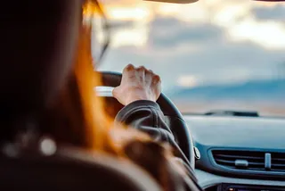 Persona al volante de un auto sedán compacto en una calle de ciudad mexicana