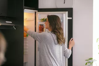Mujer sonriente toma un producto del refrigerador
