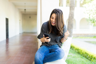 Una chica festeja un resultado deportivo mirando su celular Xiaomi