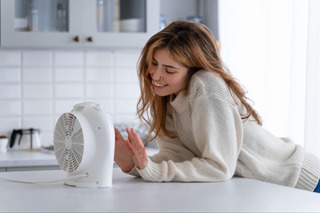 mulher estendendo a mĂŁo para o ventilador