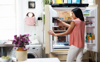 Mujer tomando un producto del refrigerador de puerta francesa