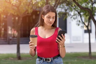 Mujer sostiene café y celular