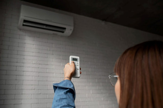 mujer enciende aire acondicionado con control remoto