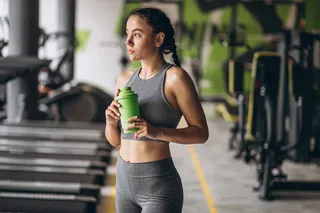 mulher com garrafa no ginásio