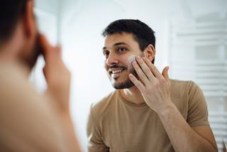 Homem faz skincare em frente ao espelho