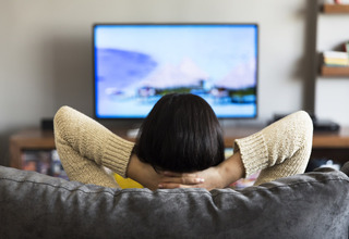 Uma mulher relaxada assistindo a um filme em sua tv lg