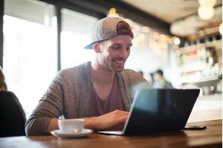 Hombre en una cafetería junto a su computador