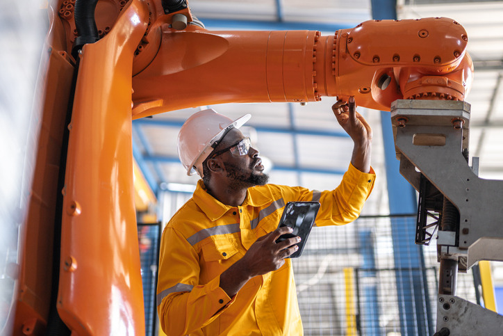 Hombre trabajador industrial actuando sobre un brazo robótico
