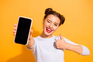 Una mujer sonriente muestra su smartphone