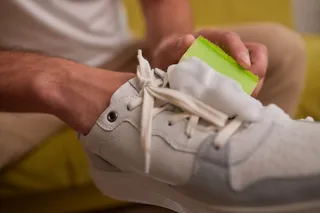 Hombre limpiando unos tenis blancos.