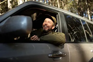 Persona sonriente al volante de una SUV compacta en carretera.