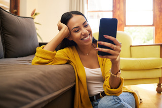 Una persona usando su celular mientras se relaja en su living