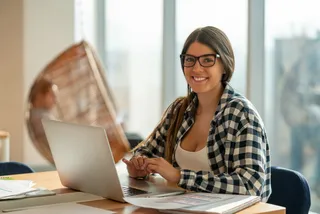 Una mujer joven con anteojos utiliza su notebook en sala de estar