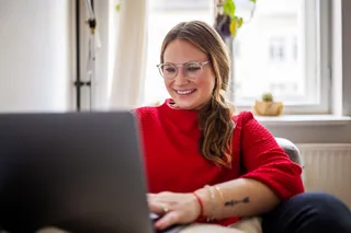 Mujer trabajando en el computador sentada en el sillón