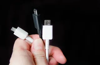 Alt: MĂŁos segurando trĂȘs cabos usb