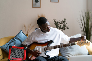 Homem afinando uma guitarra Fender.