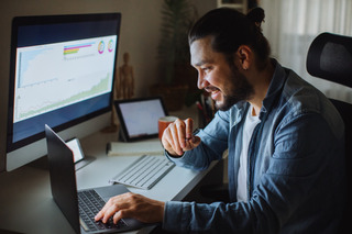 Un hombre trabaja desde su casa con sus dos computadoras