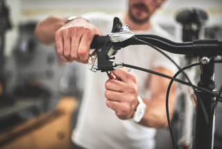 Homem ajusta sistema de freios de uma bicicleta