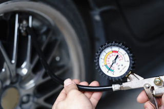 Persona utilizando un medidor de presión para chequear su neumático