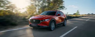 Mazda CX-30 Turbo 2024 en color Soul Red Crystal de perfil, sobre carretera pavimentada.