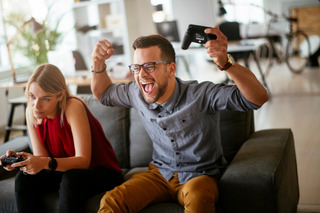 Homem comemora enquanto joga vídeo game com uma mulher