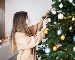 Una niña decora un árbol de Navidad