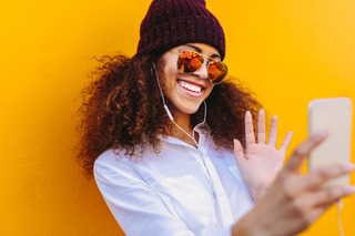 Mujer sonriente sacándose una selfie con su celular