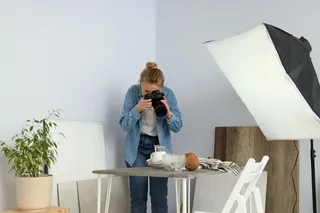 Mulher em estúdio caseiro tirando foto de alimentos.